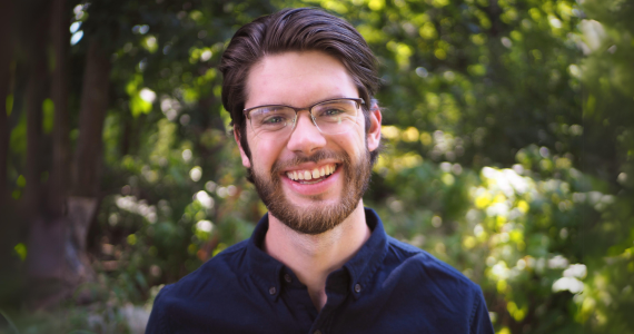 Patrick smiling outdoors amongst greenery
